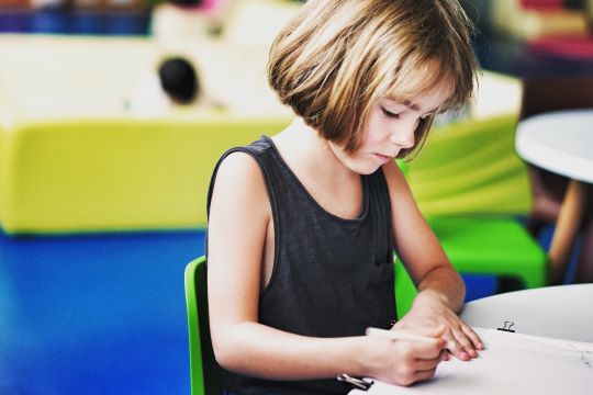 jeune fille qui aide à lire à une petite fille pendant un babysitting à Paris 7